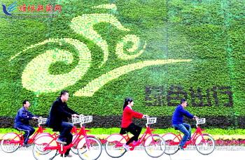 市民騎公共自行車路過市人民廣場(chǎng)一處花壇。記者 張馳
